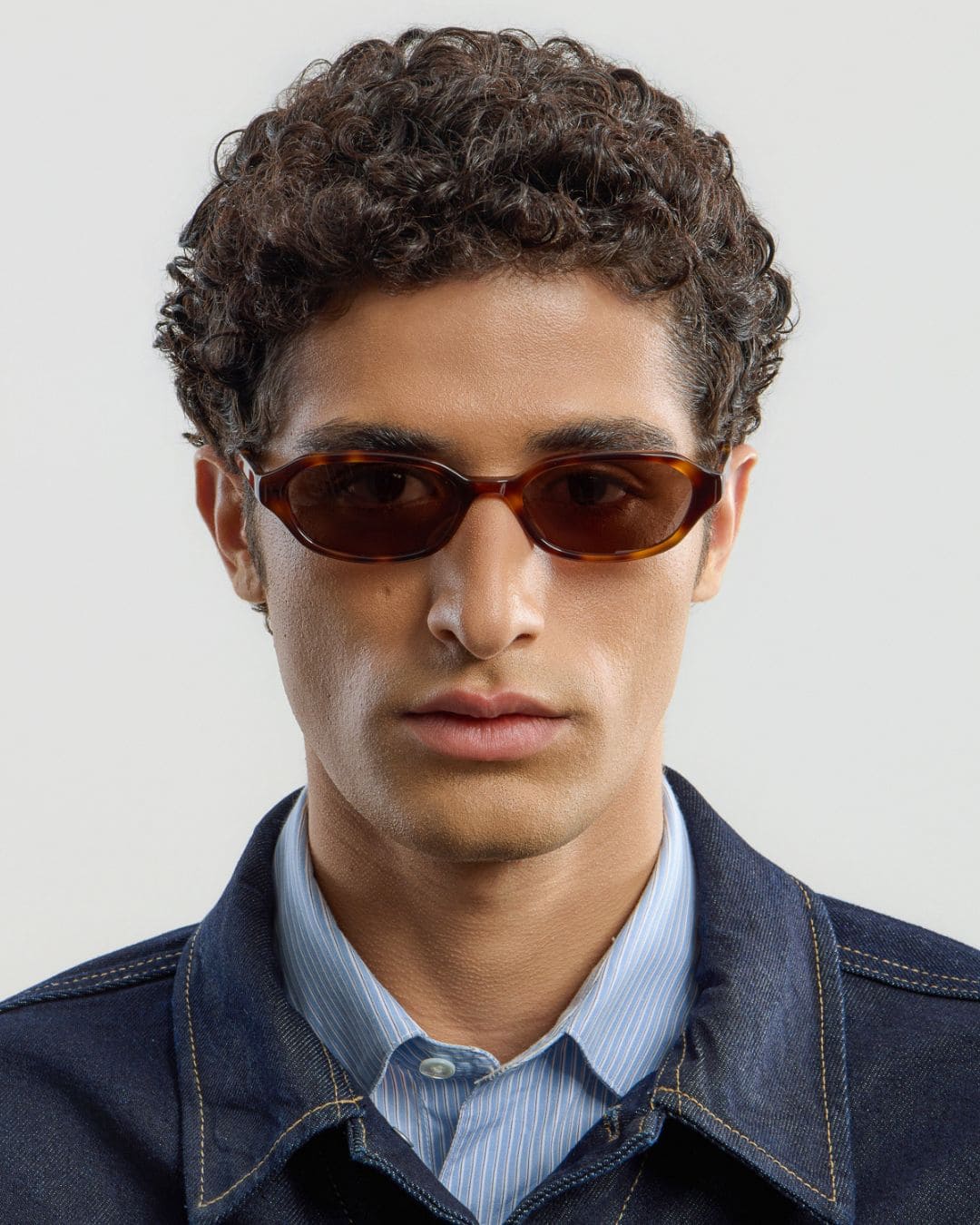 Man wearing tortoise brown sunglasses with a neutral background