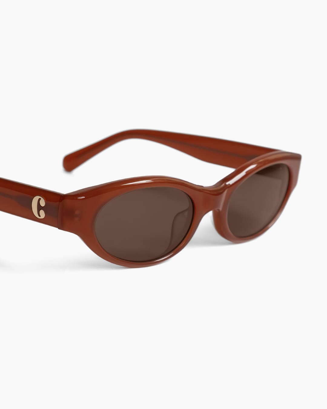 Closeup of red brown sunglasses with a logo on a white background