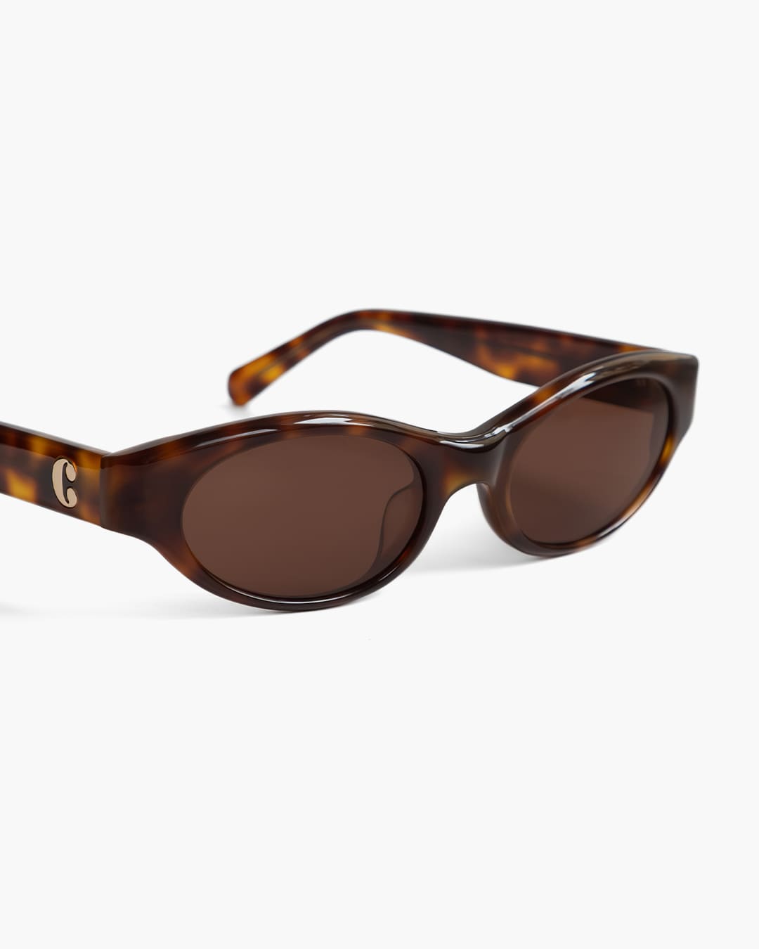 Closeup of sunglasses with tortoiseshell frame and brown lenses on a white background