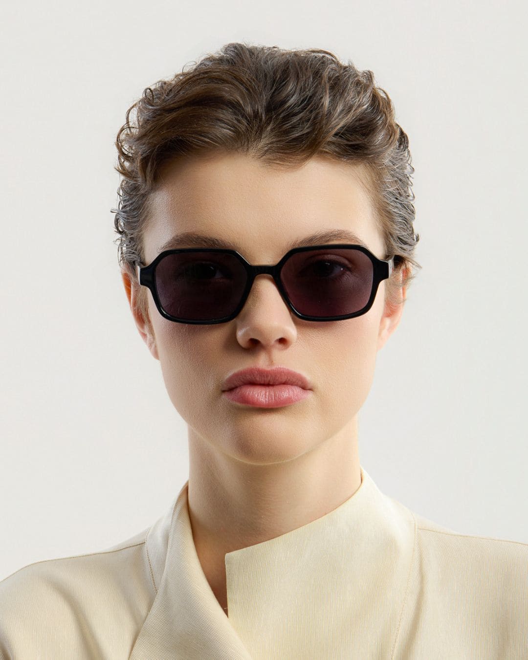 Person wearing black sunglasses with a plain background
