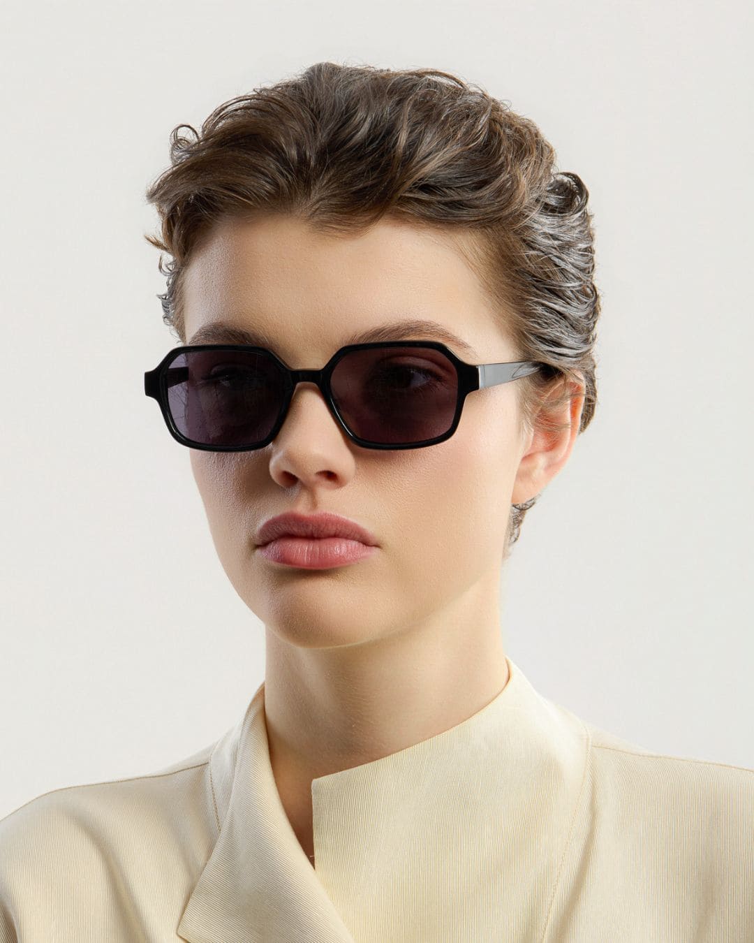 Woman wearing black sunglasses with a neutral background