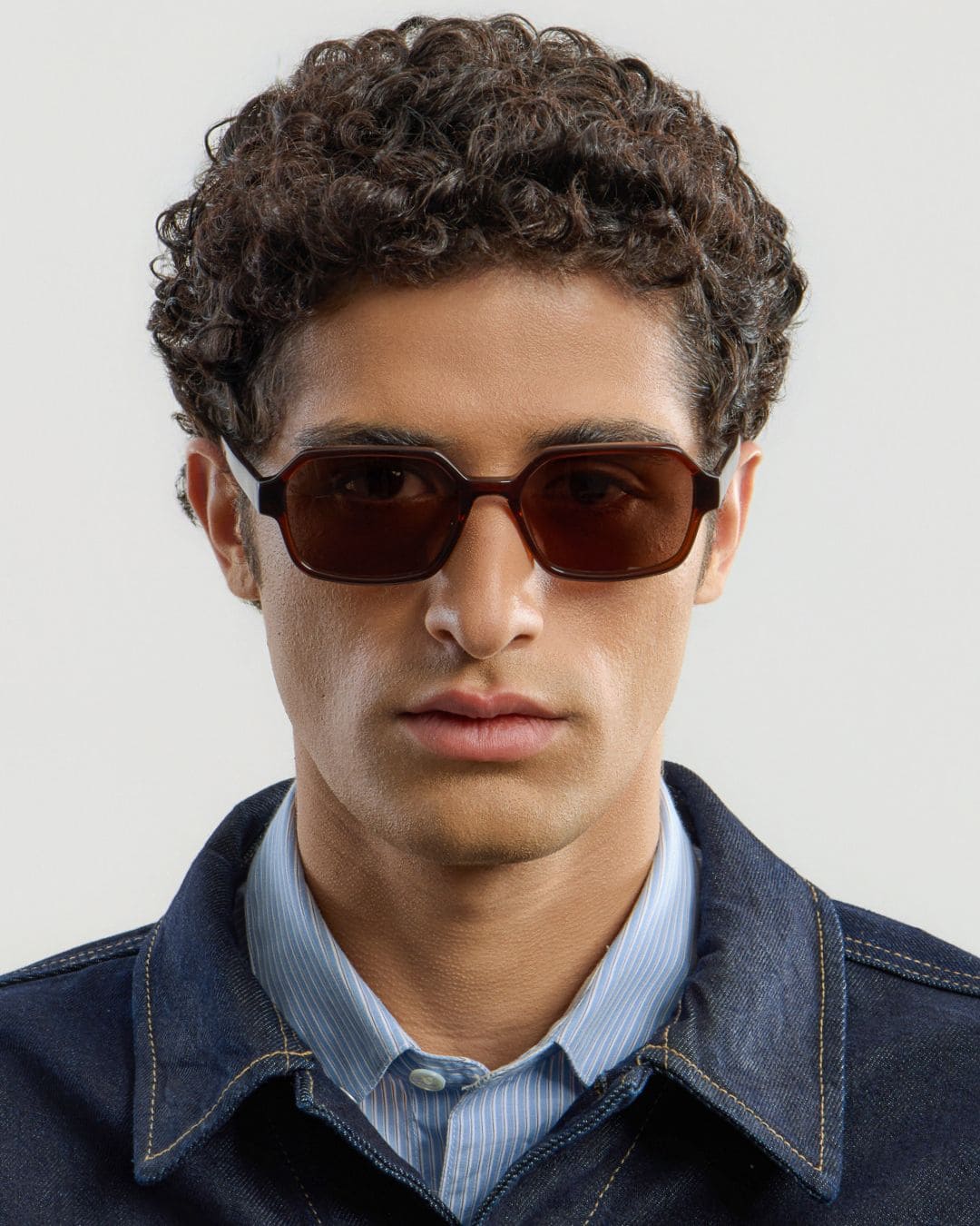 Man wearing brown sunglasses with a plain background