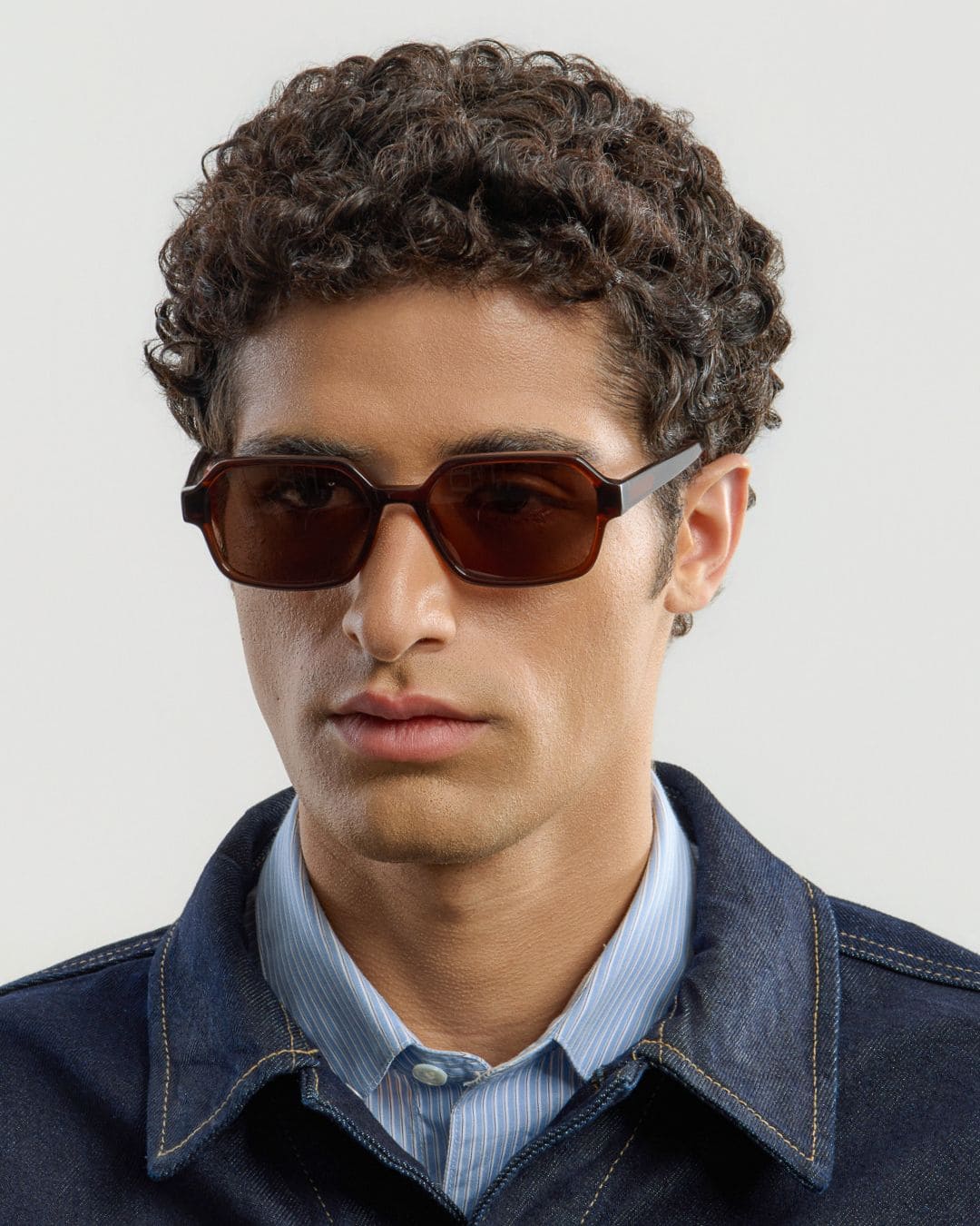 Man wearing brown sunglasses with a neutral background