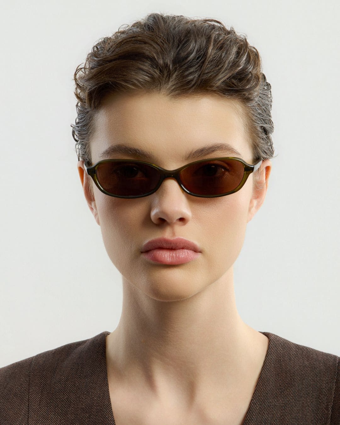 Female model wearing Corlin Eyewear Ana Olive Brown sunglasses — front view, subtle cat-eye lift