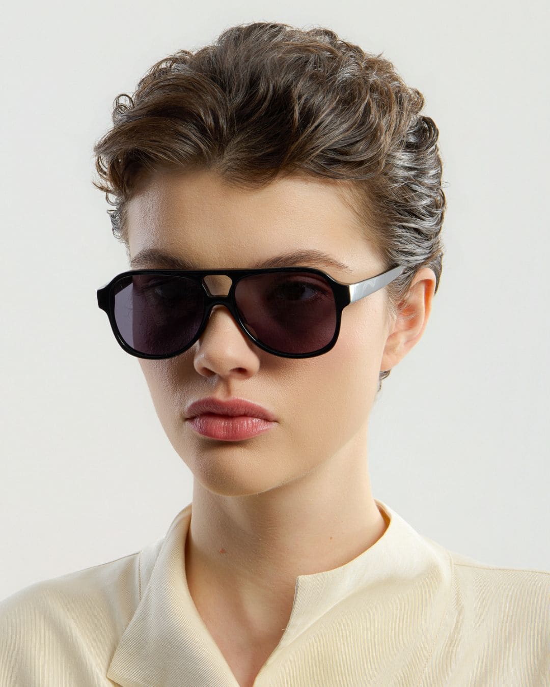 Woman wearing black sunglasses against a light background
