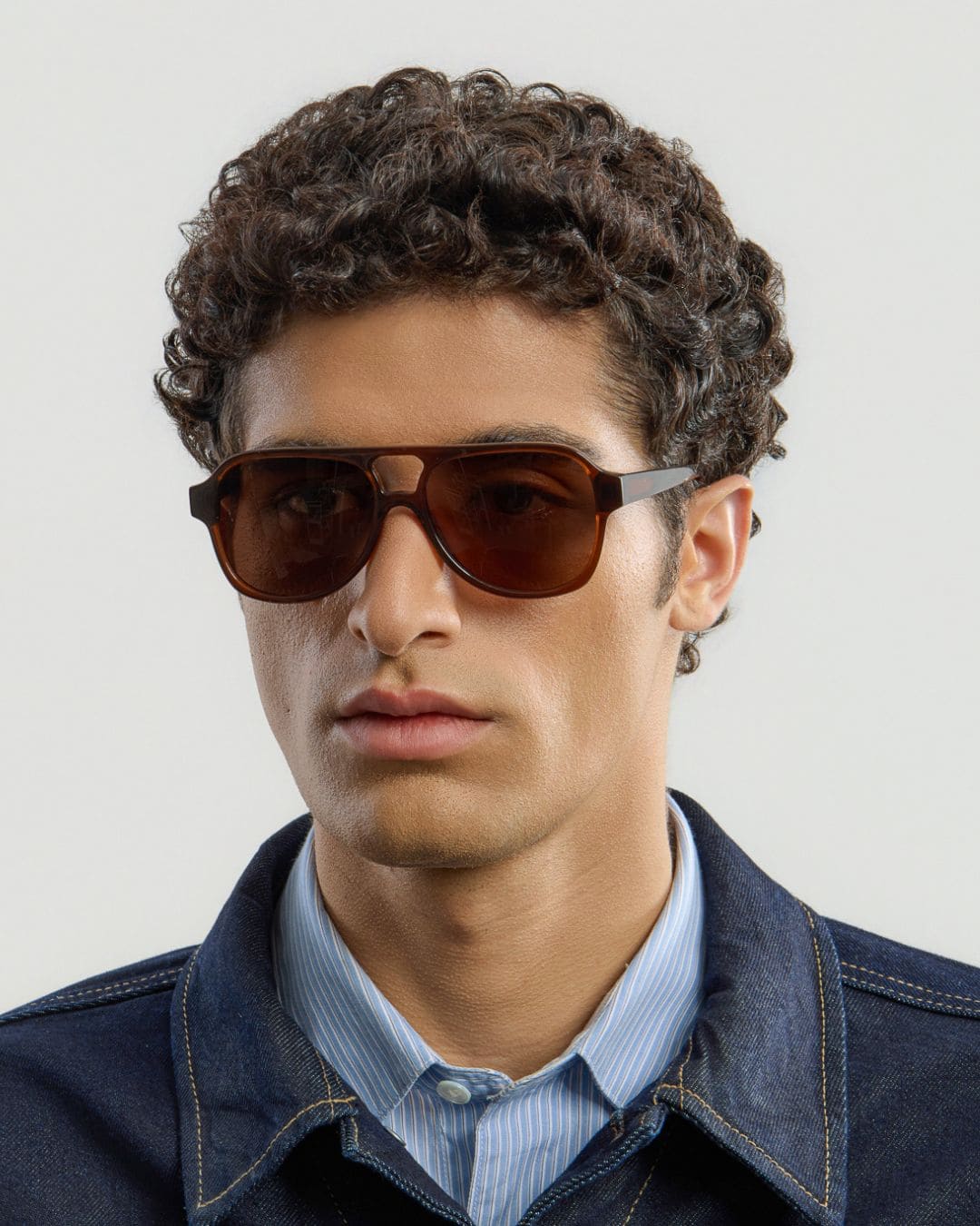Man wearing brown sunglasses with a neutral background