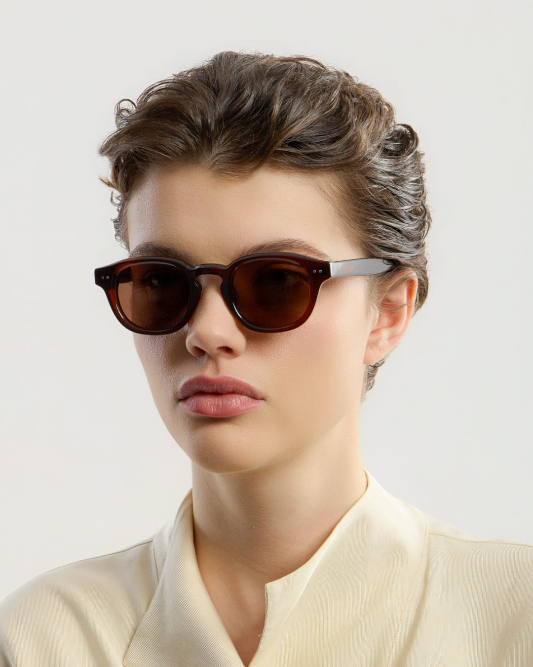 Person wearing brown sunglasses with a neutral background