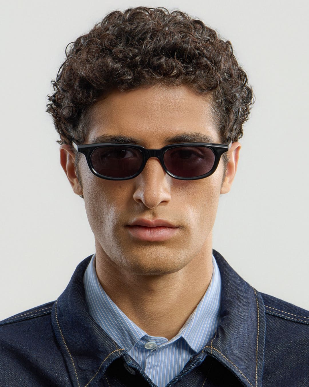Male model wearing Corlin Eyewear Jean Black Black sunglasses — front view, slim unisex acetate frame