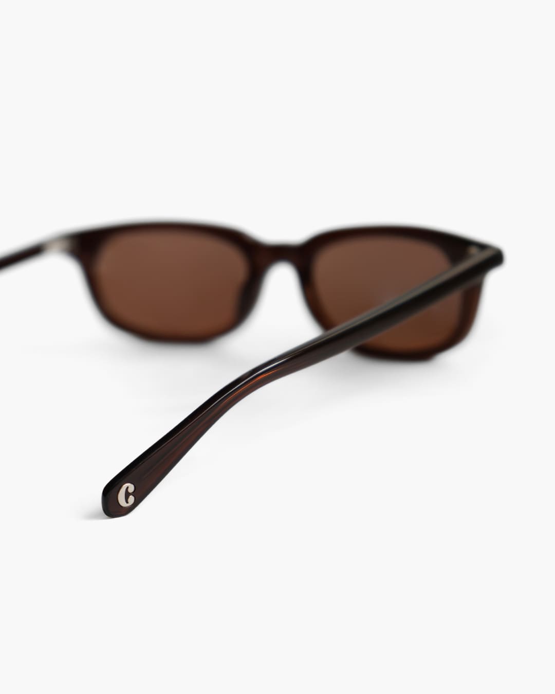 Brown sunglasses with a blurred background focusing on the logo