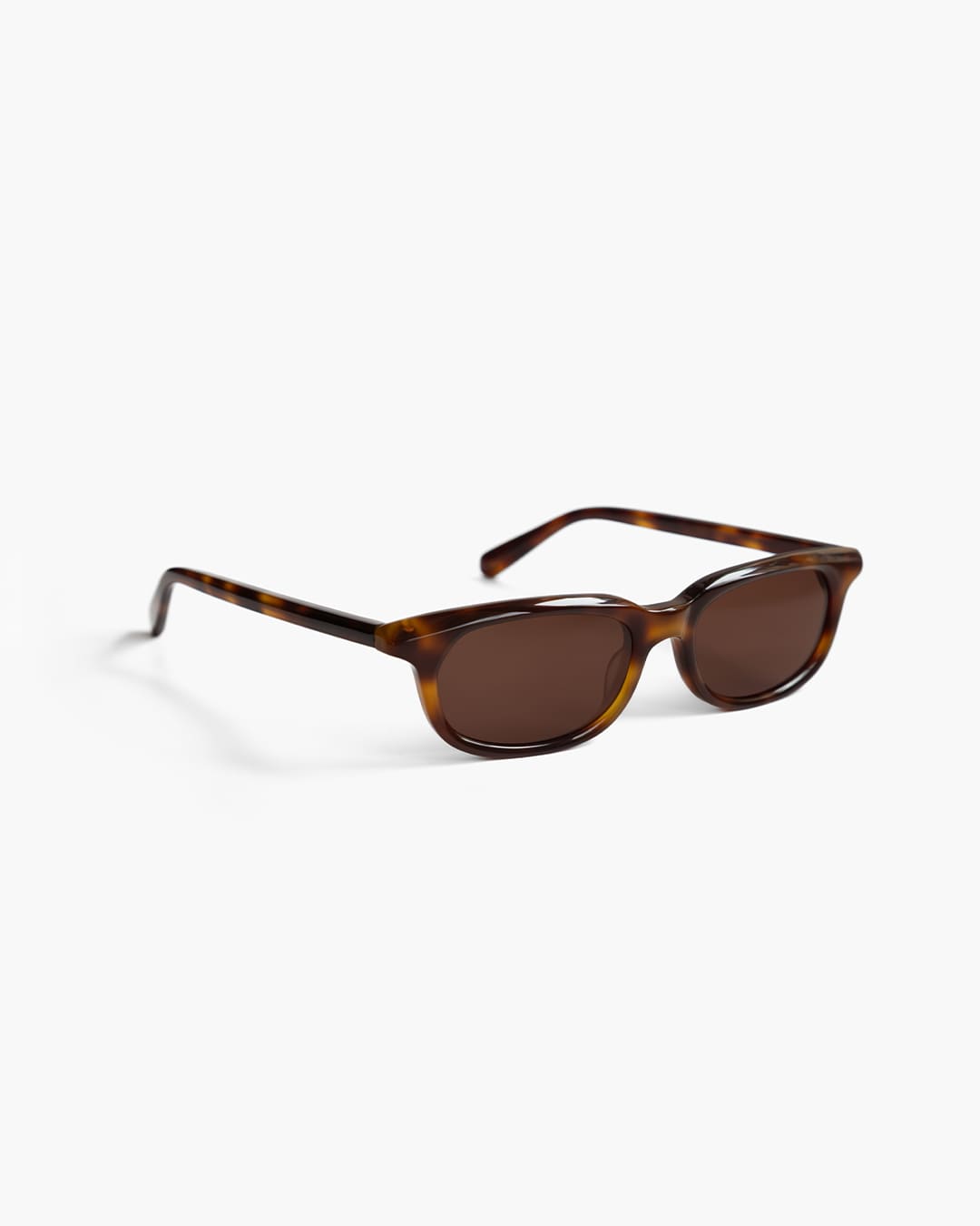Sunglasses with tortoiseshell frame and dark lenses on a white background slightly from the side