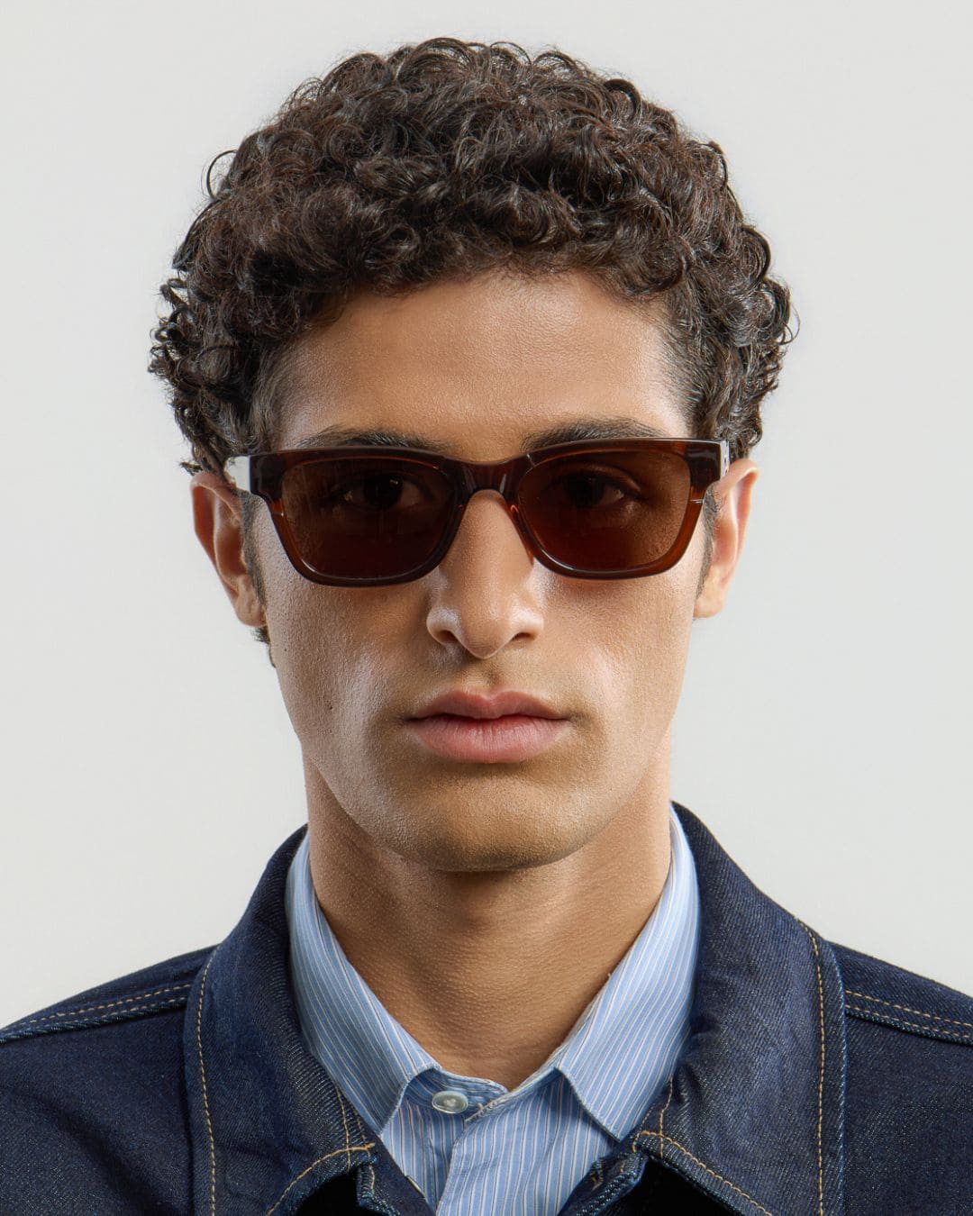 Man wearing brown sunglasses with a neutral background