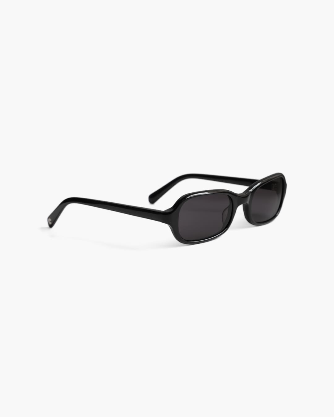 Sunglasses with a dark frame and dark lenses on a white background slightly from the side