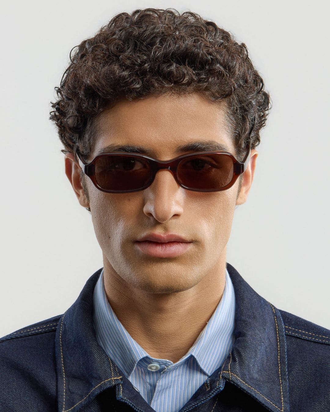Man wearing brown sunglasses with a neutral background