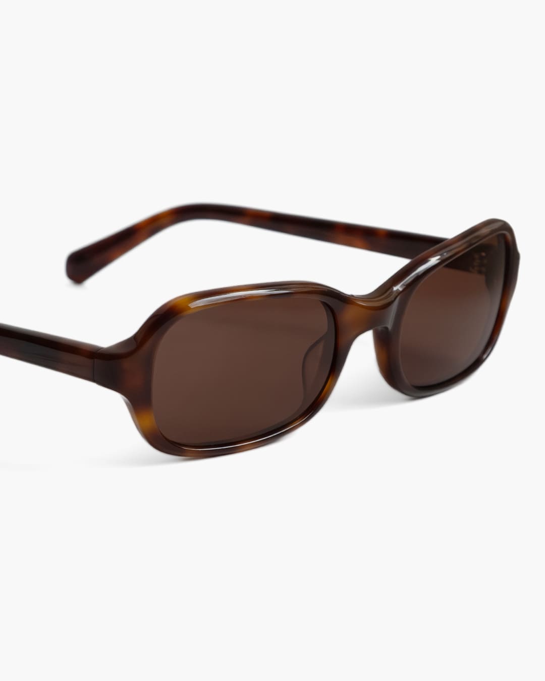 Closeup of sunglasses with tortoiseshell frame and brown lenses on a white background