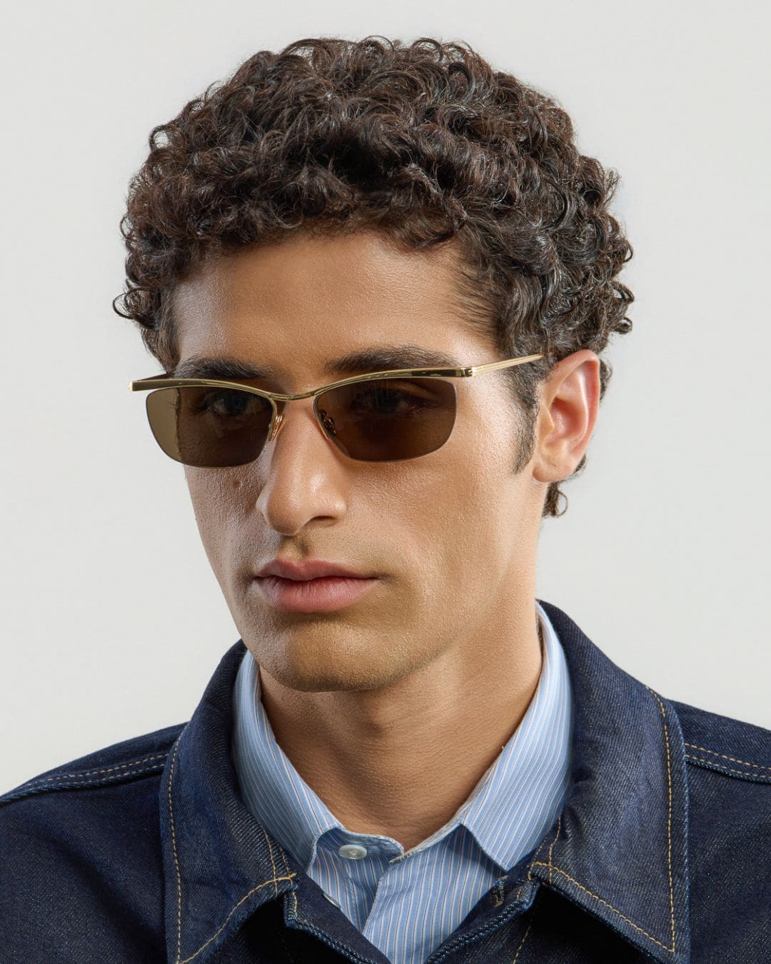 Man wearing gold brown sunglasses with a neutral background