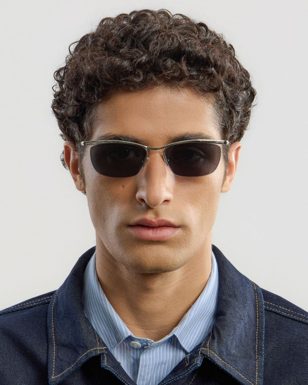 Man wearing silver black sunglasses with a plain background