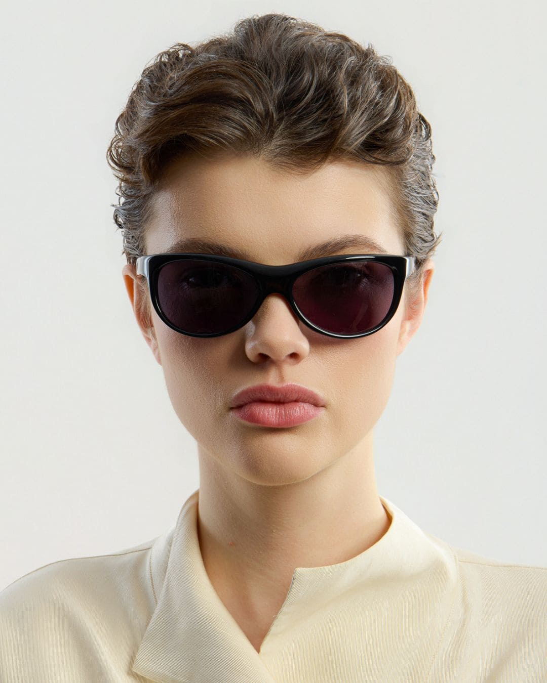 Female model wearing Corlin Eyewear Lynne Black sunglasses — front view, Italian acetate wraparound frame