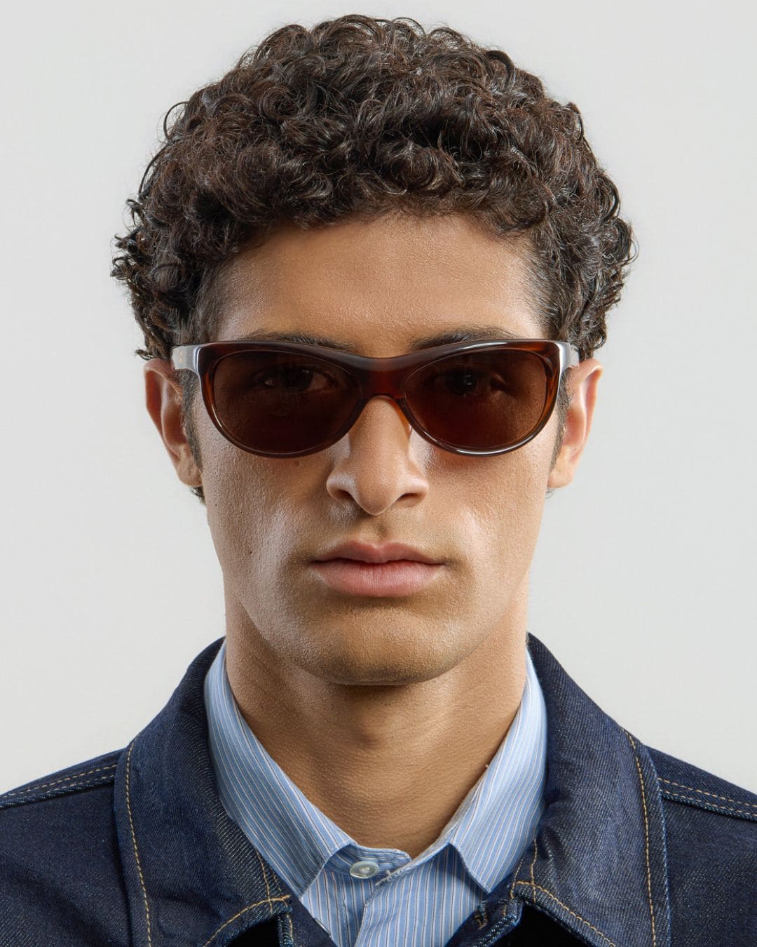 Female model wearing Corlin Eyewear Lynne Brown Brown sunglasses — front view, Italian acetate wraparound frame
