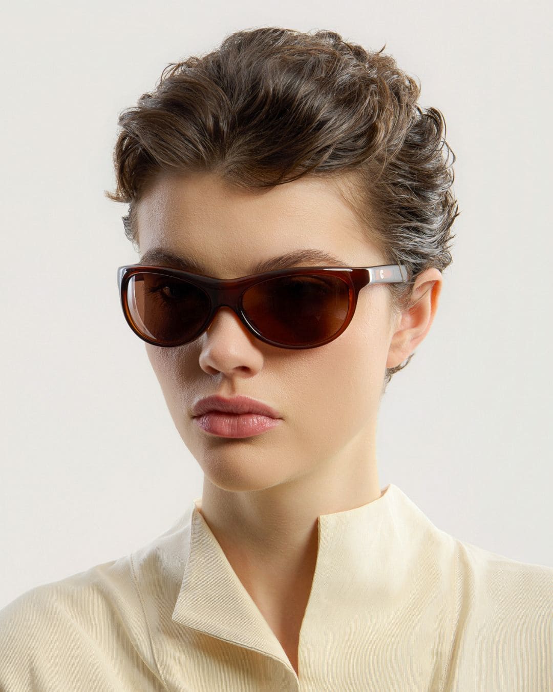 Female model wearing Corlin Eyewear Lynne Brown Brown sunglasses — side profile, Swedish minimalist wraparound design