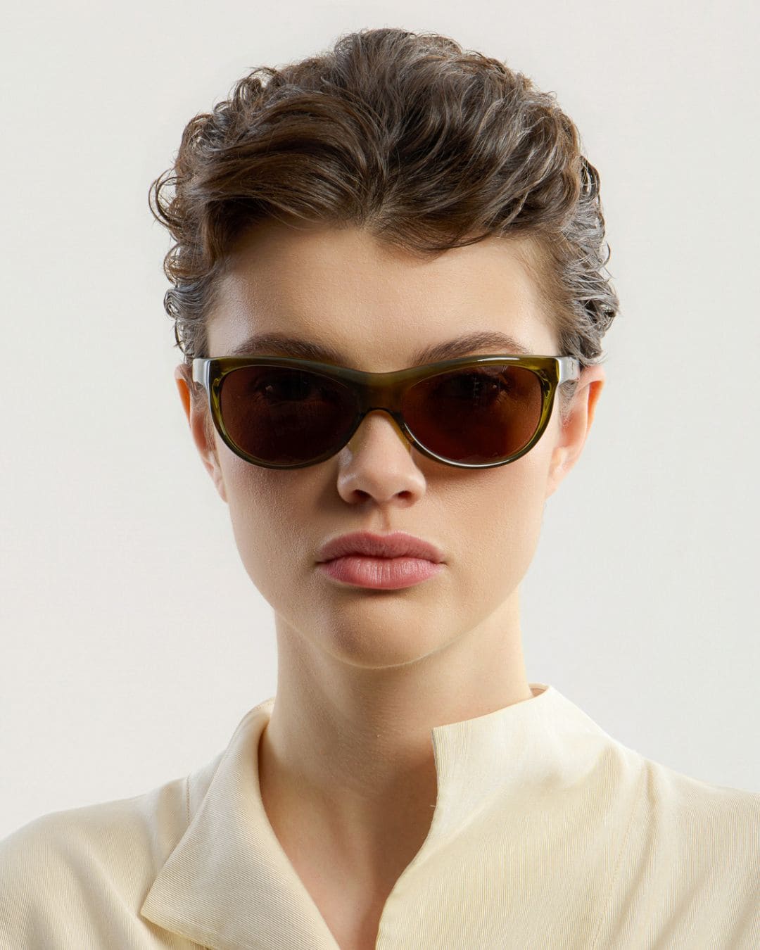 Female model wearing Corlin Eyewear Lynne Olive Brown sunglasses — front view, Italian acetate wraparound frame