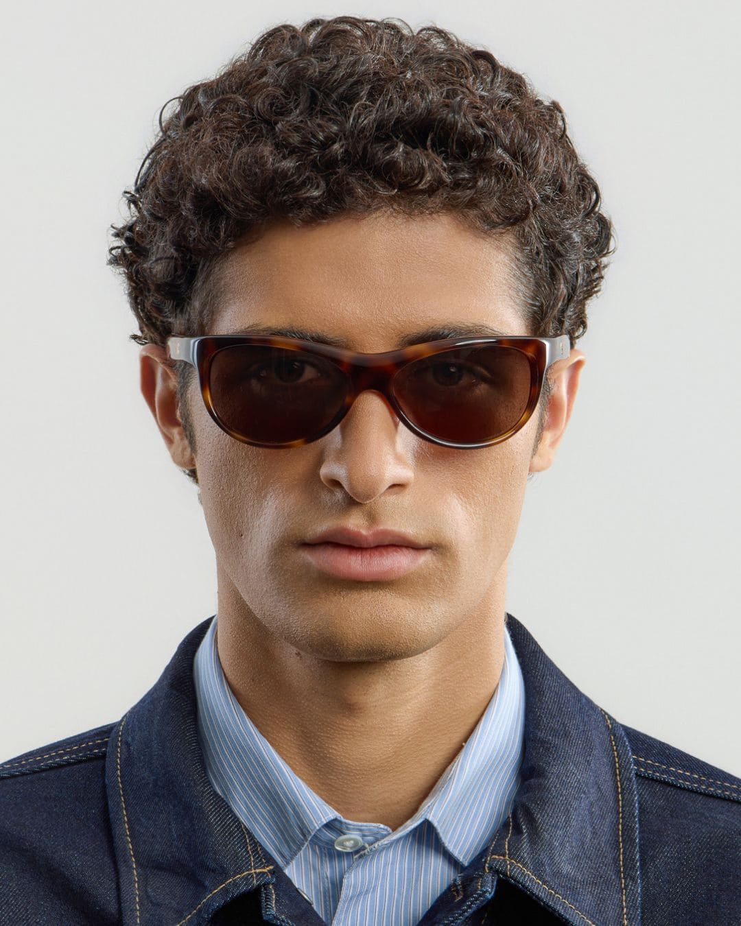 Male model wearing Corlin Eyewear Lynne Tortoise Brown sunglasses — front view, sculpted wraparound fit
