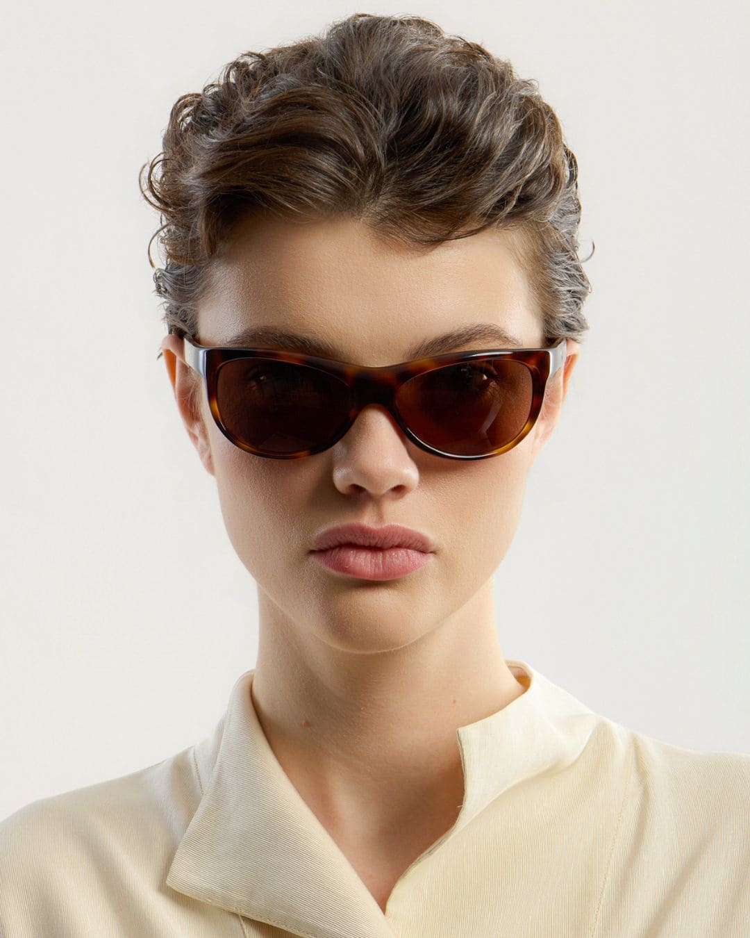 Female model wearing Corlin Eyewear Lynne Tortoise Brown sunglasses — front view, Italian acetate wraparound frame