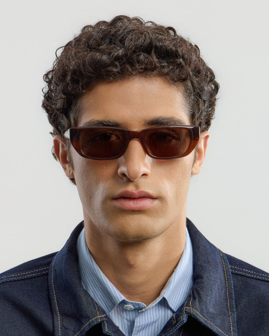 Man wearing brown sunglasses with a plain background