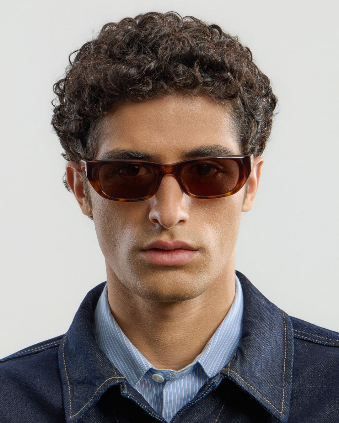 Man wearing tortoise brown sunglasses with a neutral background