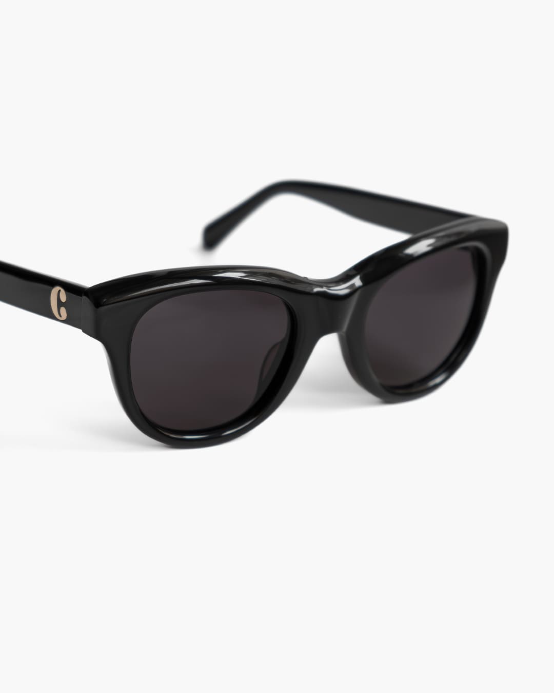 Closeup of black sunglasses with a logo on a white background