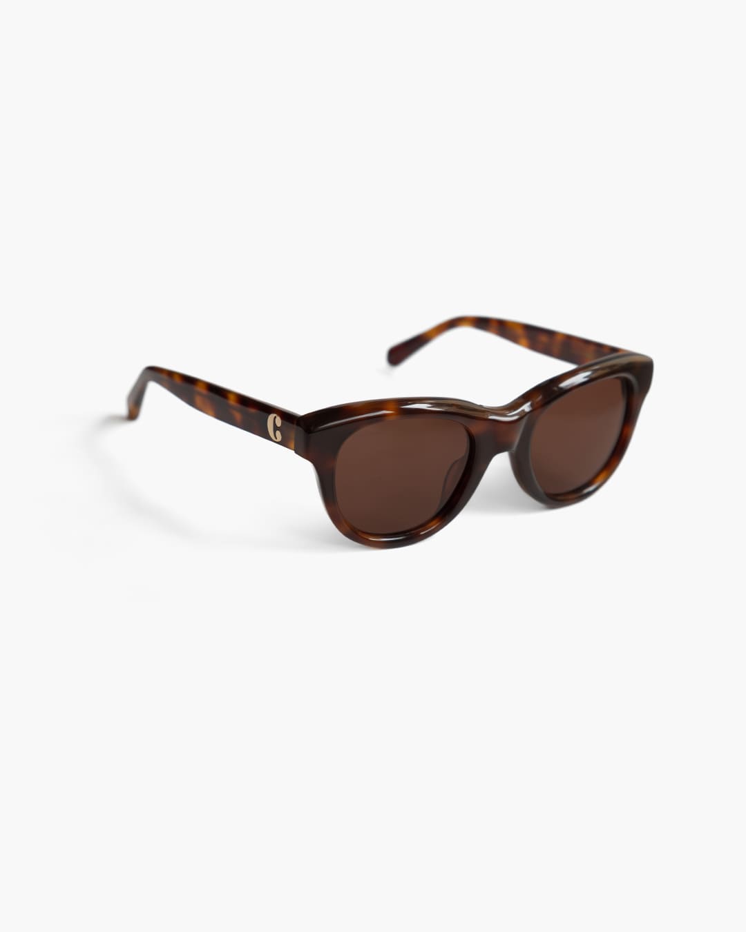 Sunglasses with tortoiseshell frame and brown lenses on a white background slightly from the side