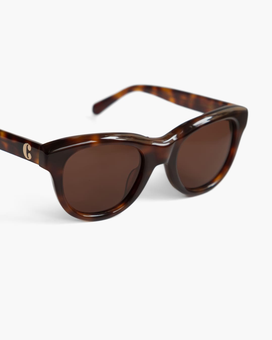 Closeup of tortoiseshell sunglasses with brown lenses on a white background