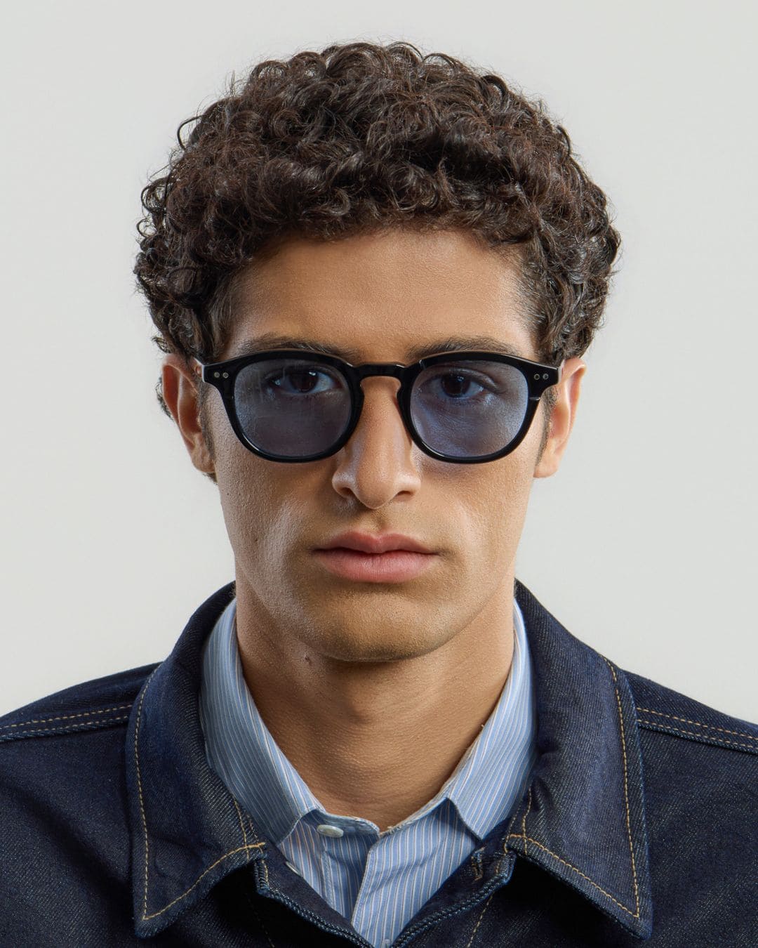 Man wearing black blue glasses with a plain background