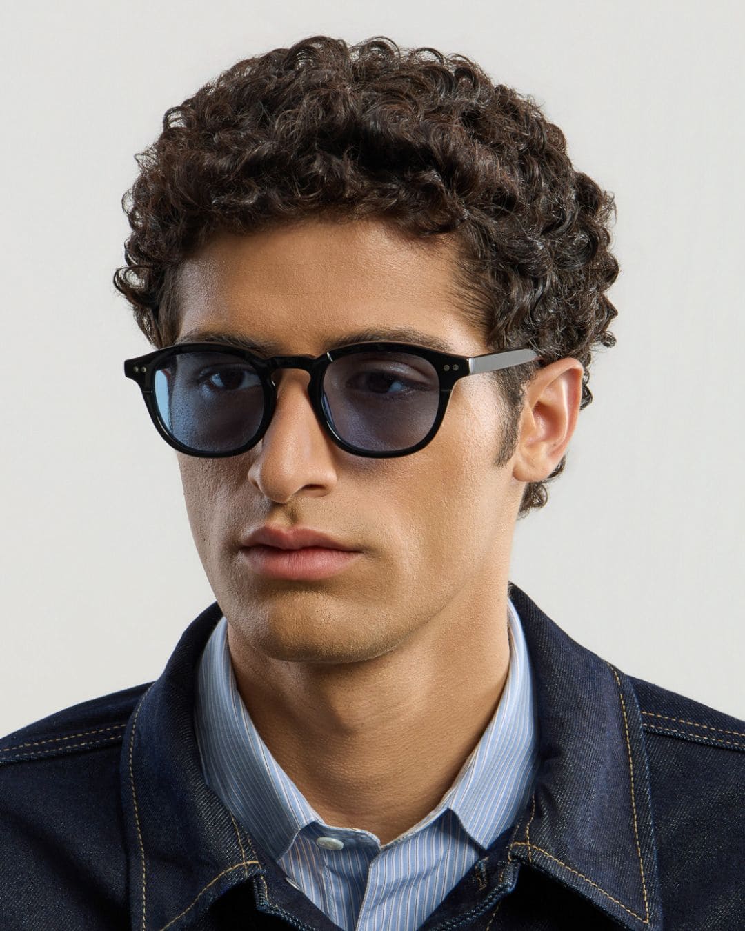 Man wearing black blue sunglasses with a neutral background