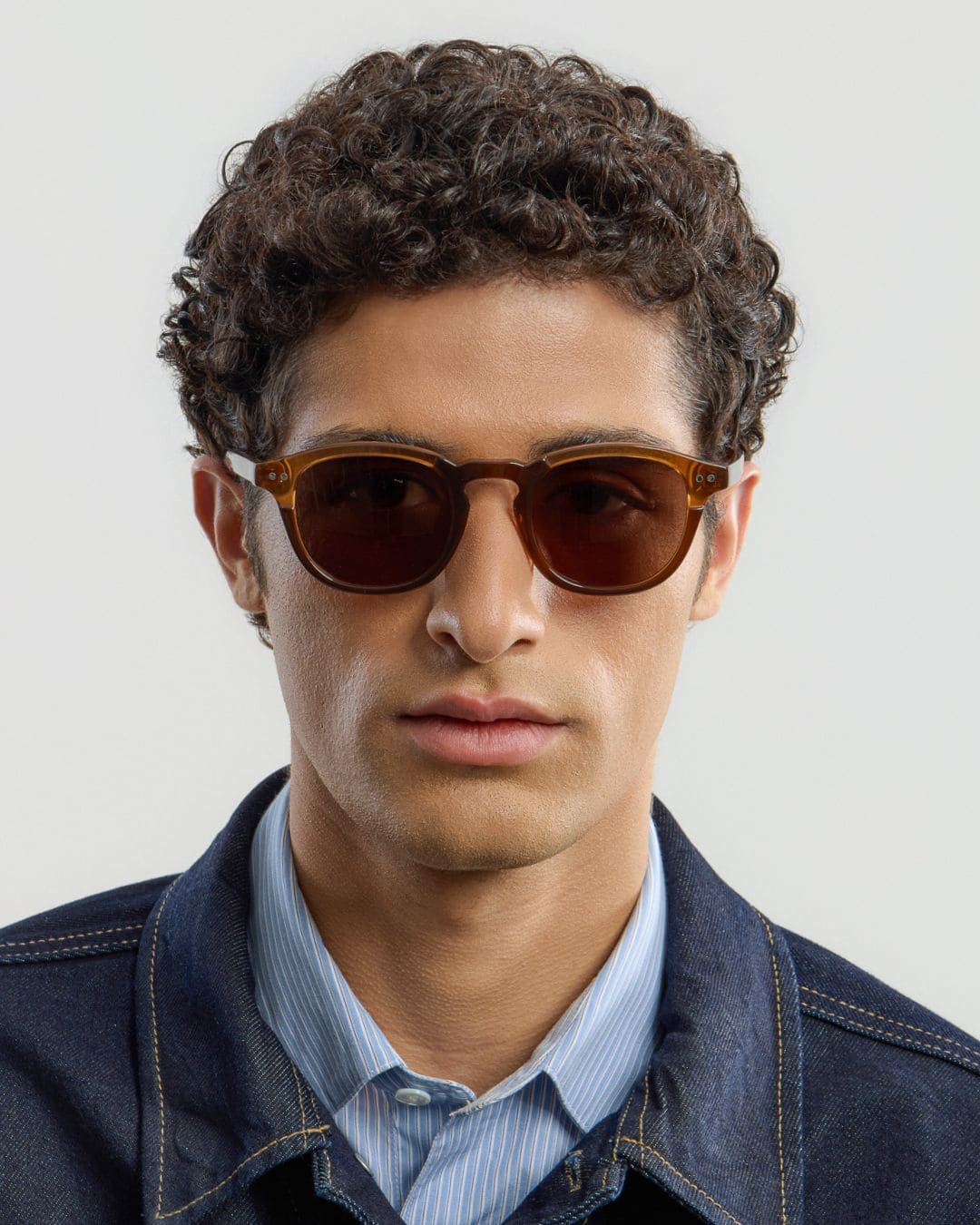 Man wearing brown sunglasses with a plain background