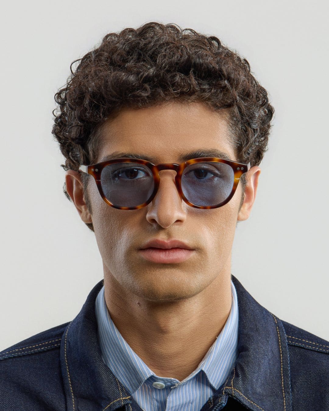 Man wearing tortoise blue glasses with a neutral background