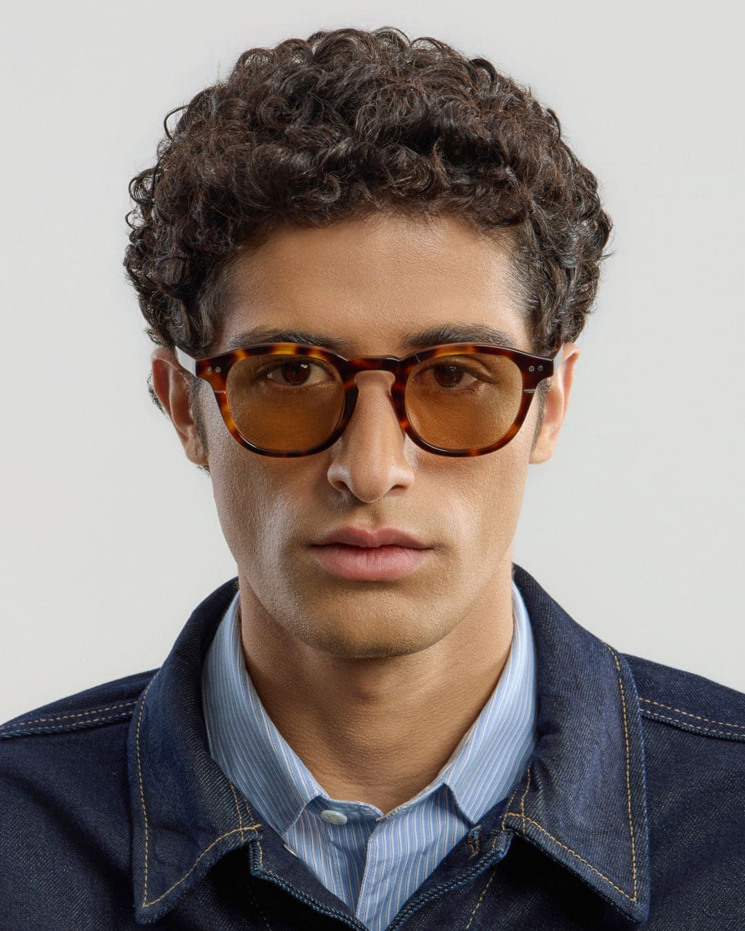 Man wearing tortoise cinnamon sunglasses with a neutral background